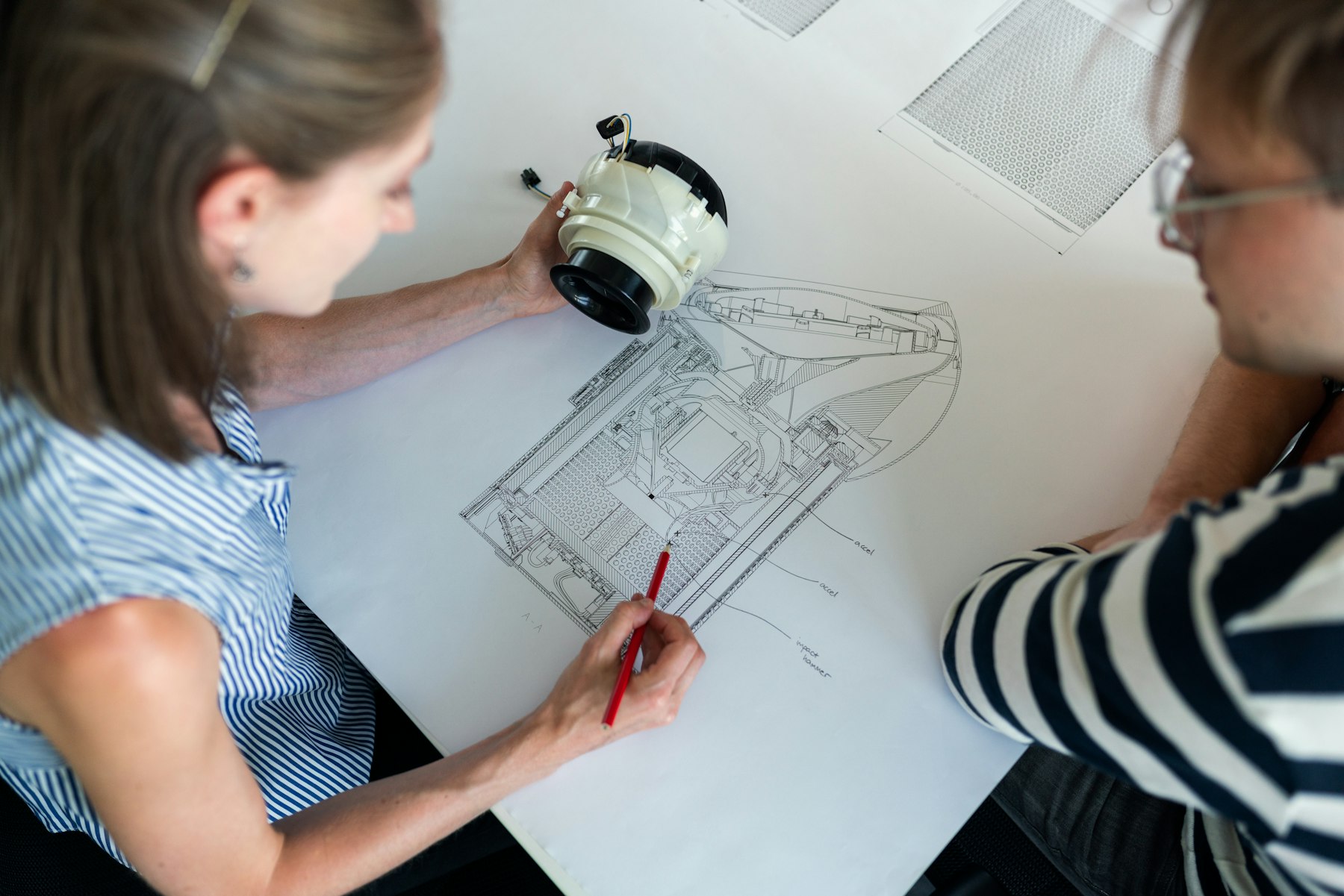 Engineering team reviewing technical schematics, representing ongoing AI operations review